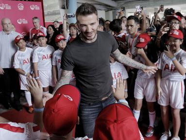 Legenda sepak bola Inggris, David Beckham, menyapa fans cilik di Stadion Soemantri Brodjonegoro, Jakarta, Minggu (25/3/2018). AIA membagikan 10.000 bola kepada akademi sepak bola di Indonesia. (Bola.com/M Iqbal Ichsan)
