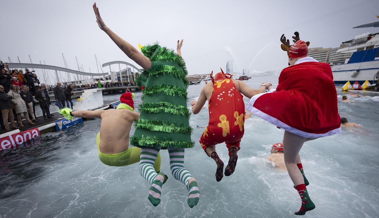 Sejumlah peserta berkostum khas hari Natal melompat ke dalam air dalam ajang Copa Nadal yang berlangsung di Barcelona's Port Vell, Barcelona, Kamis (25/12/2025) waktu setempat. Acara tersebut diikuti lebih dari 450 peserta. (AFP/Josep Lago)