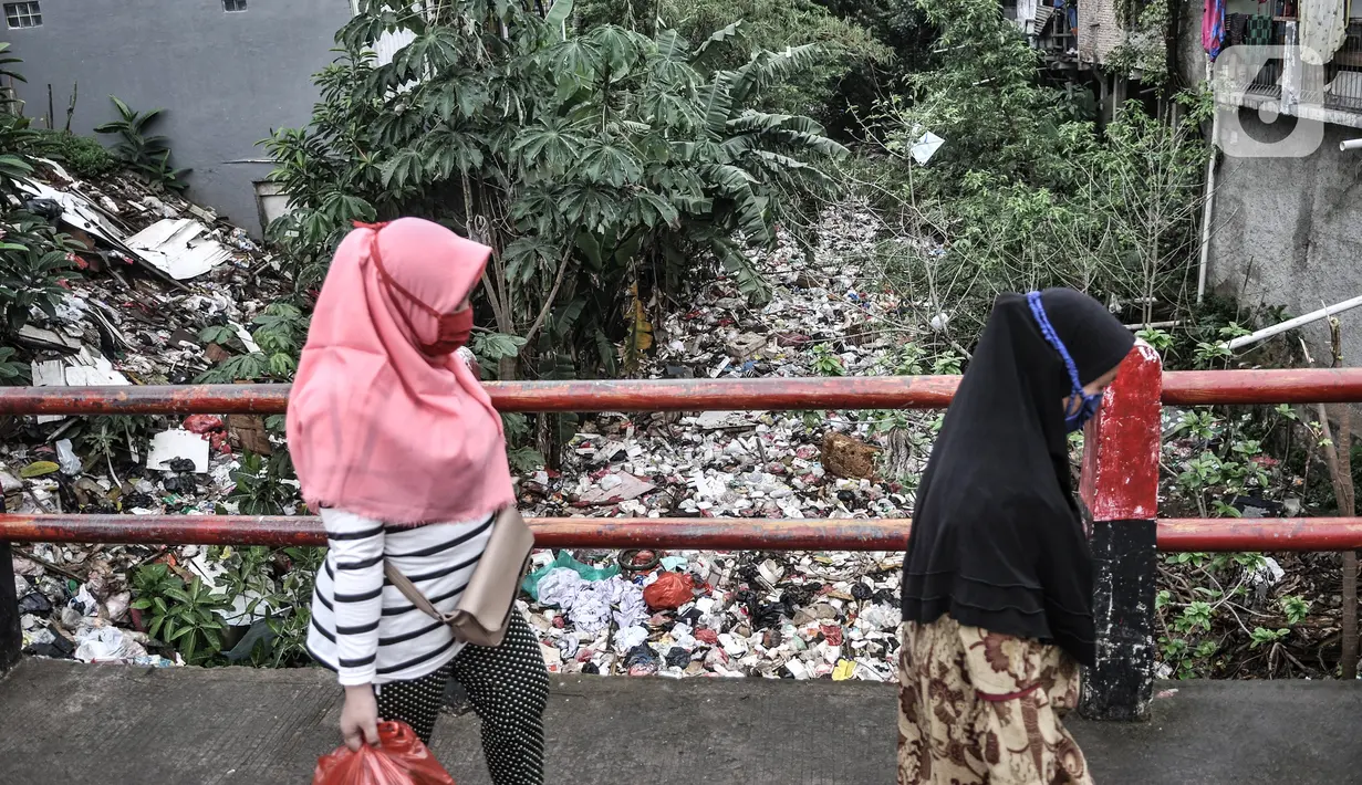 Warga melintasi aliran Kali Baru yang dipenuhi sampah di Jalan Raya Bogor, Cimanggis, Depok, Jawa Barat, Minggu (24/1/2021). Sudah lebih dari 5 bulan sampah yang didominasi limbah rumah tangga dan batang pepohonan memenuhi aliran Kali Baru hingga sepanjang 300 meter. (merdeka.com/Iqbal S. Nugroho)