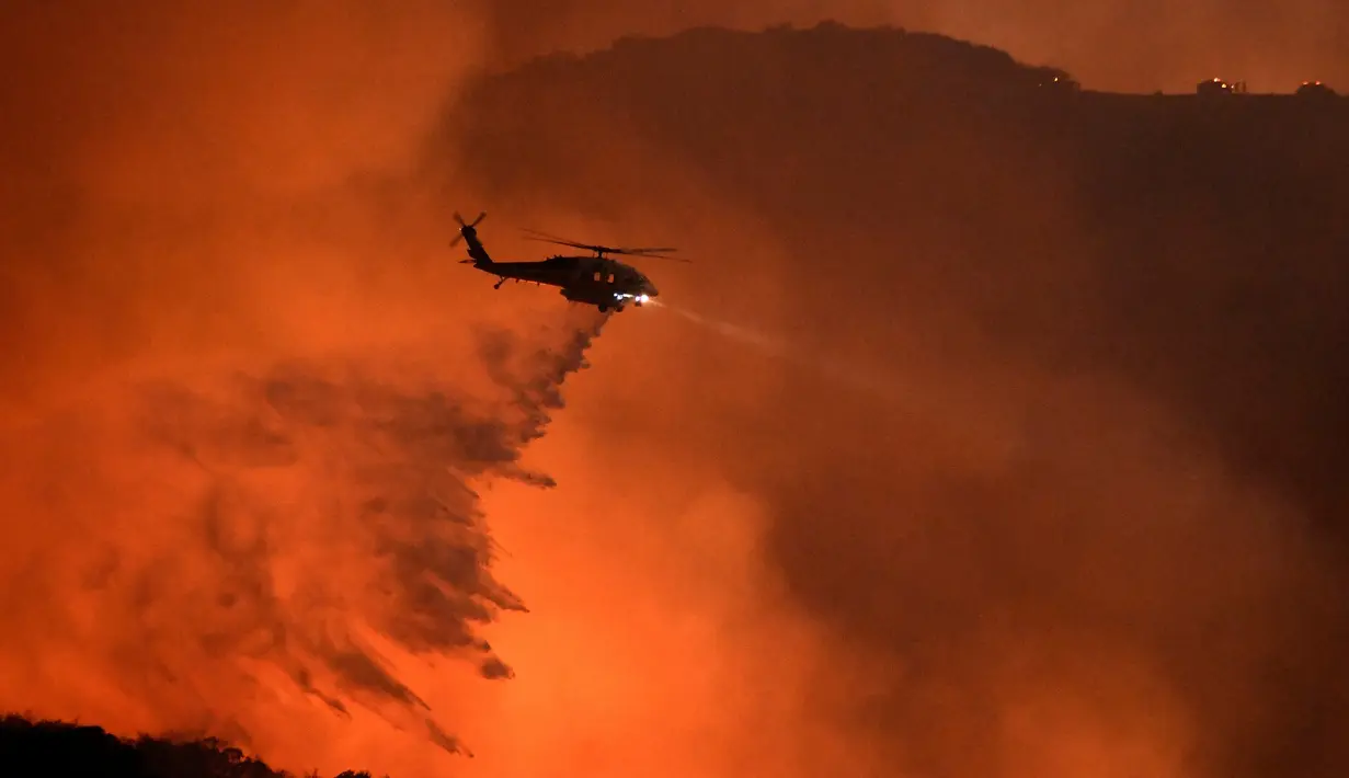 Helikopter menumpahkan air untuk memadamkan pada kebakaran hutan yang terjadi di Calabasas , California , AS , 4 Juni 2016. Ribuan warga di evakuasi ketempat lebih aman untuk menghindari korban jiwa.  ( REUTERS / Gene Blevins)