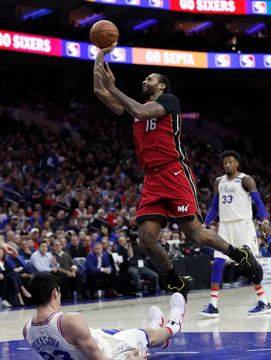 Pemain Miami Heat, James Johnson (kanan) mecetak poin saat melewati adangan pemain Philadelphia 76ers, Ersan Ilyasova pada NBA basketball playoff series di Wells Fargo Center, Philadelphia, (16/4/2018). Heat menang 113-103. (AP/Chris Szagola)