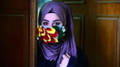 Seorang perempuan mengenakan topeng yang dihiasi kelopak bunga di tengah virus corona (Covid-19) di pusat kota suci Najaf, Irak pada 21 Maret 2020. Masker dijadikan masyarakat pilihan untuk mencegah penyebaran pandemi virus corona yang terus meningkat di seluruh dunia. (Haidar HAMDANI/AFP)