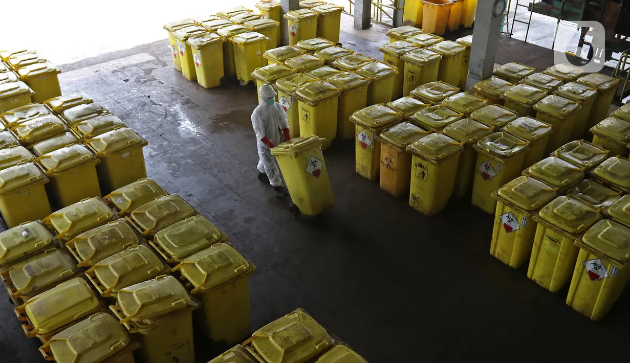 Petugas membawa "Wheeled Bin" atau tempat sampah berisi limbah B3 medis Infeksius Covid-19 untuk dimusnahkan di PT Jasa Medivest, Karawang, Jawa Barat, Kamis (10/12/2020).  PT Jasa Medivest telah memusnahkan lebih dari 500 ton limbah B3 medis dari Maret - Oktober 2020. (Liputan6.com/Herman Zakharia)