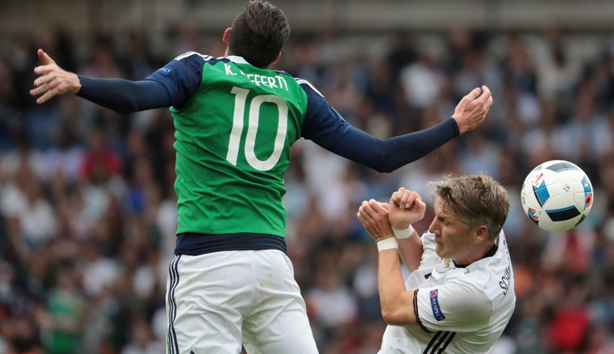 Pemain Jerman, Bastian Schweinsteiger, duel dengan pemain Irlandia Utara, Kyle Lafferty, pada laga Grup C Piala Eropa 2016 di Parc des Princes, Paris, Selasa (21/6/2016). (AFP/Kenzo Tribouillard)