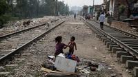 Seorang anak perempuan anak muda memandikan saudaranya di sebelah jalur gerobak api di New Delhi, India, Selasa (16/10). Hasil survei terhadap 104 negara yang dirilis bulan lalu mendapatkan bahwa sekitar 1,3 miliar orang hidup dalam kemiskinan. (AP Photo/Altaf Qadri)