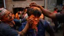 Warga menaburkan bubuk vermillion saat perayaan sindoor Jatra festival di Bhaktapur, Nepal (15/4). Dalam festival tersebut warga Nepal menaburkan serbuk berwarna oranye untuk merayakan 'Sindoor Jatra'. (AP Photo/Niranjan Shrestha)