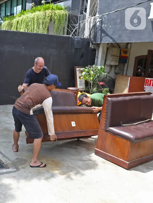 Pegawai bersama seorang warga negara asing membersihkan sisa-sisa banjir di salah satu bar di kawasan Kemang Raya, Jakarta, Kamis (2/1/2020). Para pegawai mulai membersihkan ruangan yang terendam air pascabanjir yang melanda Kemang Raya. (Liputan6.com/Herman Zakharia)