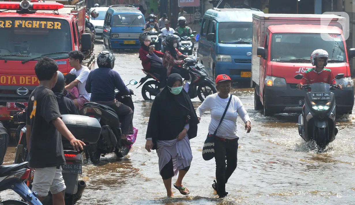 Pengendara dan pejalan kaki melewati banjir yang menggenangi kawasan perempatan Mampang, Depok, Jawa Barat, Rabu (18/05/20222). Banjir tersebut disebabkan meluapnya Kali Mampang. Menurut pejabat setempat, banjir terjadi akibat adanya batang pohon yang tersangkut di kolong jembatan Mampang. (merdeka.com/Arie Basuki)