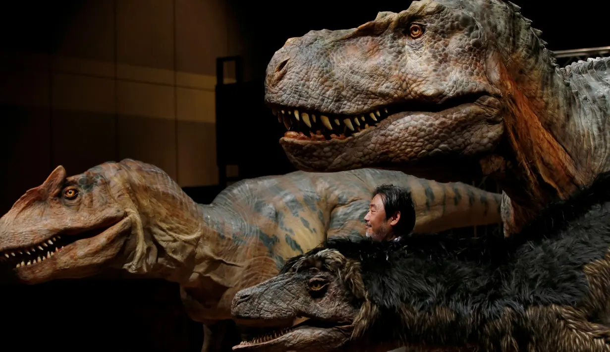 CEO perusahaan On-Art Corp berpose dengan sejumlah robot dinosaurus yang diperkenalkan di aula pertemuan sebuah hotel di Tokyo, Jepang, Kamis (10/11). Robot TRX03 itu memiliki berat 38 kilogram dengan panjang hingga 8 meter. (REUTERS/Toru Hanai)