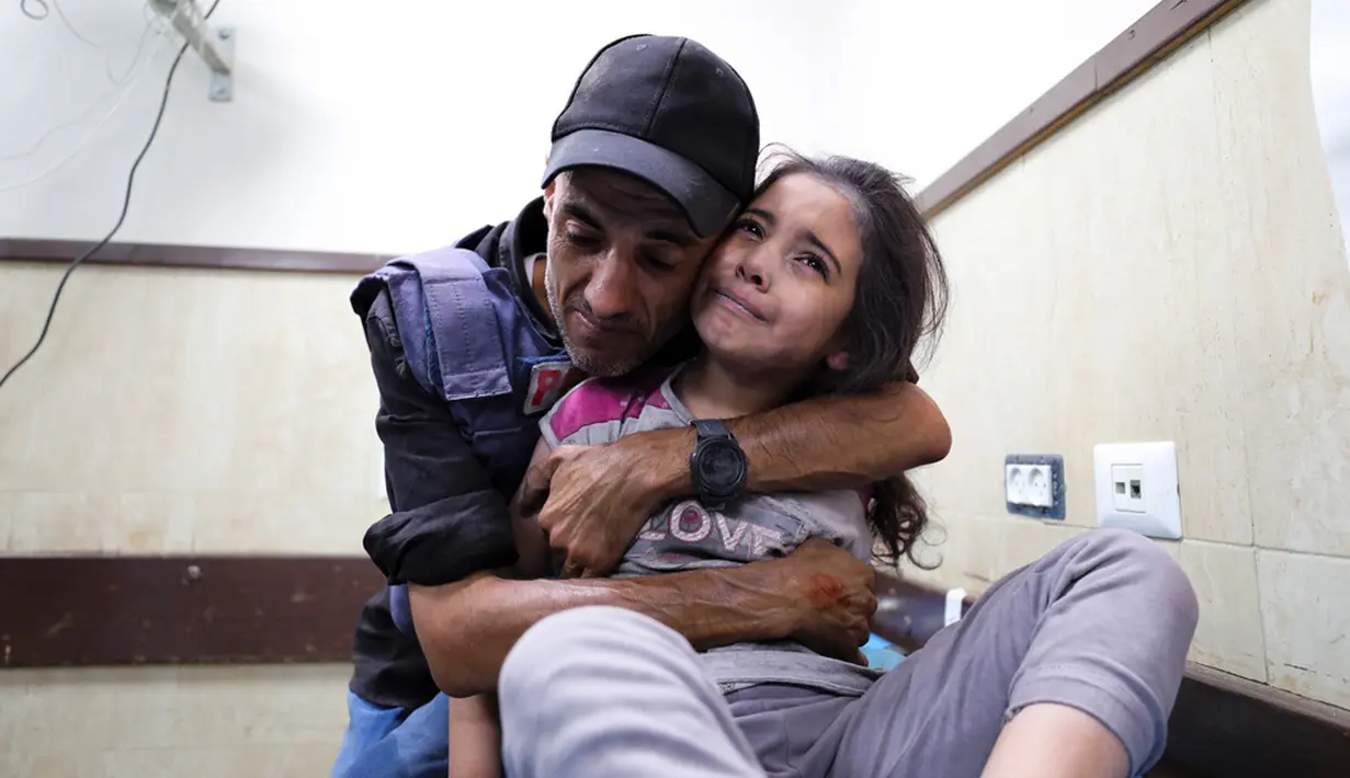 Seorang jurnalis Palestina menghibur keponakannya yang terluka dalam serangan Israel di rumah keluarganya di kamp pengungsi Nusseirat di sebuah rumah sakit di Deir el-Balah, Jalur Gaza, Minggu (22/10/2023). (AP Photo/Ali Mahmoud)