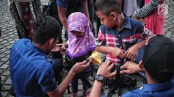 Petugas pemadam kebakaran memasang alat pengaman pada tubuh anak yang akan mencoba wahana flying fox di area Monas, Jakarta, Selasa (1/1). Pengunjung dapat menikmati wahana ini secara gratis. (Liputan6.com/Faizal Fanani)