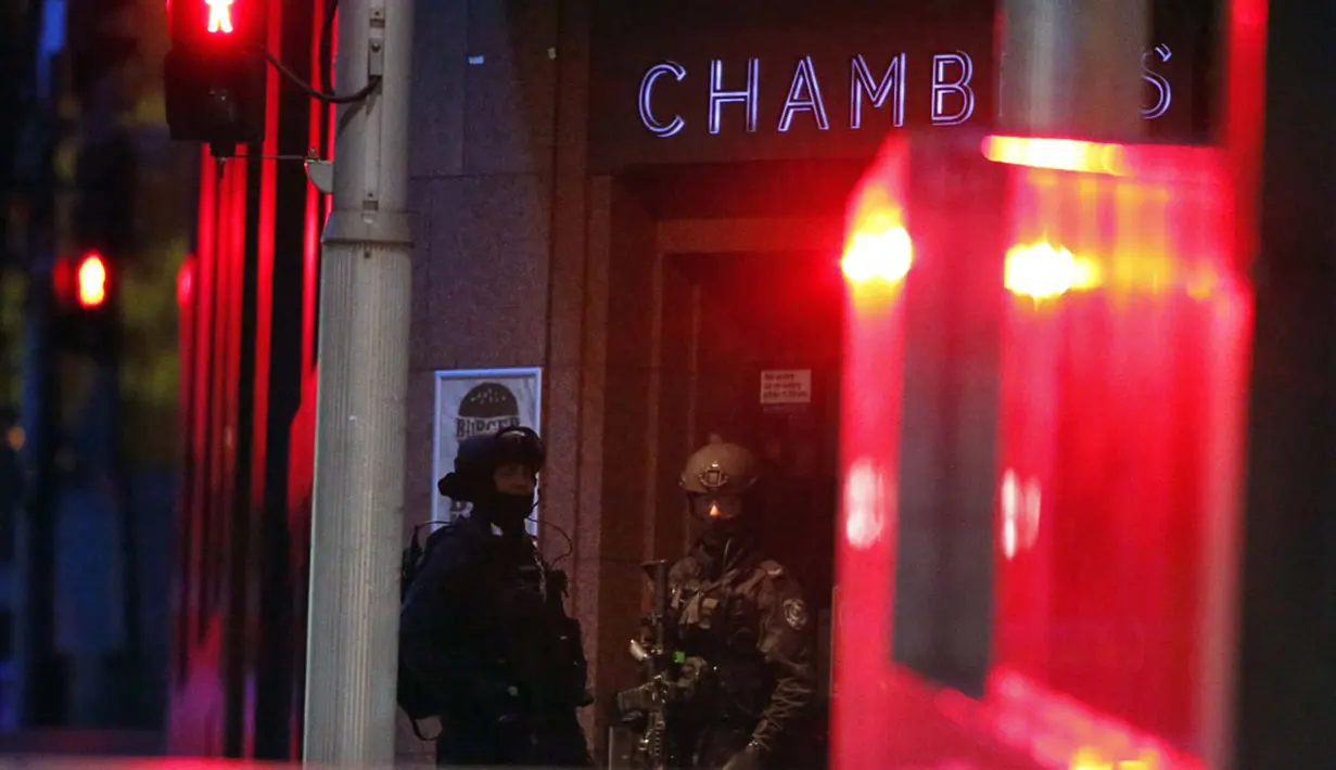 Polisi bersenjata lengkap berjaga di luar gedung yang berisi Kafe Lindt di Martin Place, Sydney (16/12/2014). Seorang pria bersenjata masuk ke Kafe Lindt dan menyandera beberapa orang yang berada di dalam kafe tersebut. (REUTERS/David Gray)
