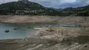 Foto ini menunjukkan sisa-sisa rumah yang muncul kembali ketika permukaan danau buatan Mornos menurun akibat kekeringan, di desa Kallio, sekitar 240 km barat laut Athena, Yunani pada 3 November 2025. Ketinggian air di danau yang terletak sekitar 240 km barat laut Athena anjlok ke titik terendah dalam 15 tahun terakhir. (Angelos TZORTZINIS/AFP)