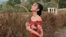 Aktris Glenca Chysara tampil memesona dengan outfit brokat off shoulder berwarna merah. Rambutnya ditata rapi, dirinya tampil candid dengan latar belakang ladang rumput kering. (Liputan6.com/IG/@glencachysaraofficial)