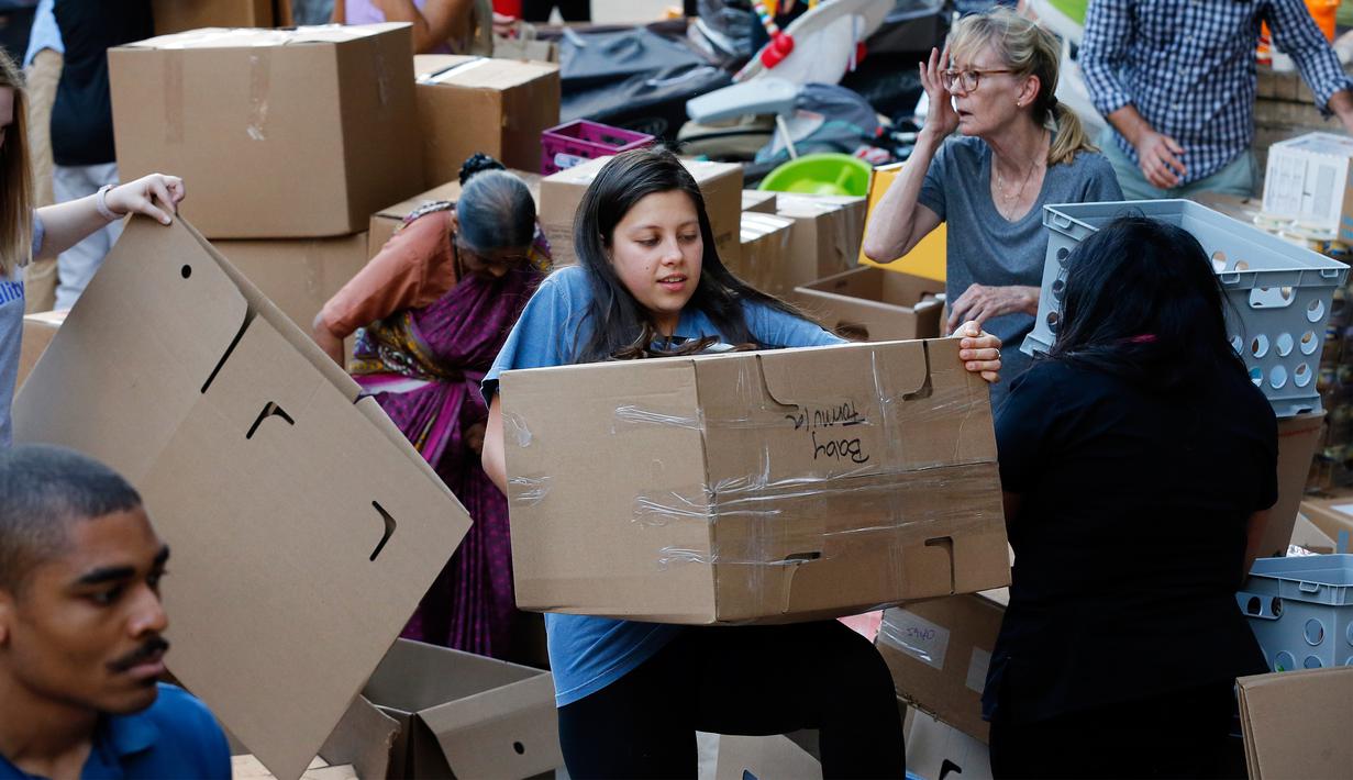 Seorang relawan membawa sekotak susu formula bayi yang diberikan untuk korban badai Harvey di pusat penggalangan dana di Dallas Utara, Selasa (29/8). Sebuah organisasi nirlaba Amerika Charity Navigator mengatur penggalangan dana ini. (Tony Gutierrez/AP)