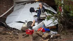 Seorang pria melangkah di atas puing-puing di dekat garasi yang dihantam tanah longsor dan banjir bandang di lingkungan pemukiman, California, pada 5 Februari 2024. (DAVID MCNEW/AFP)
