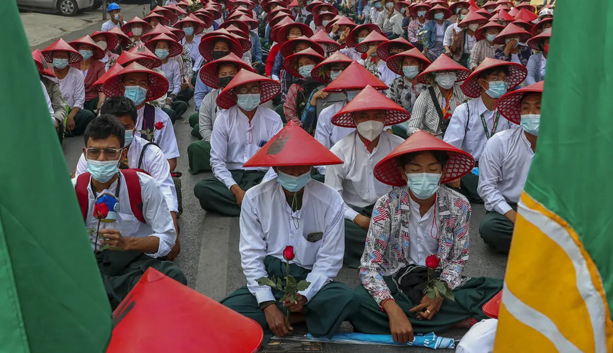 Guru sekolah antikudeta yang mengenakan seragam dan topi tradisional Myanmar duduk di jalan saat berpartisipasi dalam demonstrasi di Mandalay, Myanmar, Rabu (3/3/2021). Demonstran di Myanmar turun ke jalan lagi pada hari Rabu untuk memprotes perebutan kekuasaan bulan lalu oleh militer. (AP Photo)