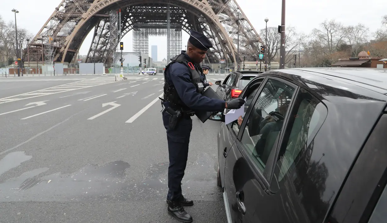 Polisi memeriksa dokumen pengemudi kendraan saat lockdown di depan Menara Eiffel, Paris, Prancis, Rabu (18/3/2020). Otoritas Prancis hanya mengizinan warga keluar rumah untuk alasan penting dan darurat. (Ludovic MARIN/AFP)
