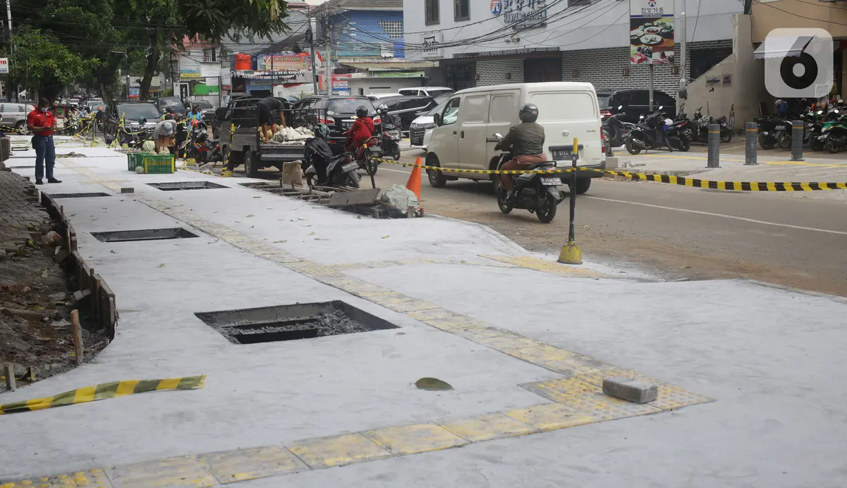 Kendaraan melintas di samping proyek revitalisasi trotoar di kawasan Senopati, Kebayoran Baru, Jakarta, Rabu (15/9/2021). Pemprov DKI Jakarta melalui Dinas Bina Marga merevitalisasi 10 ruas jalan di lima wilayah kota adminsitrasi Jakarta sampai akhir tahun 2021. (Liputan6.com/Herman Zakharia)