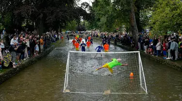 Pemain sepak bola Bourton Rovers berebut bola dalam pertandingan sepak bola tradisional tahunan River Windrush di Desa Cotswolds, Bourton-on-the-Water, Inggris, Senin (28/8/2023). (AP Photo/Frank Augstein)