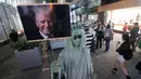 Seorang seniman jalanan berpakaian seperti Patung Liberty, memegang gambar Presiden terpilih AS, Donald Trump di pusat kota Hong Kong, Rabu (9/11). (AP Photo / Kin Cheung)