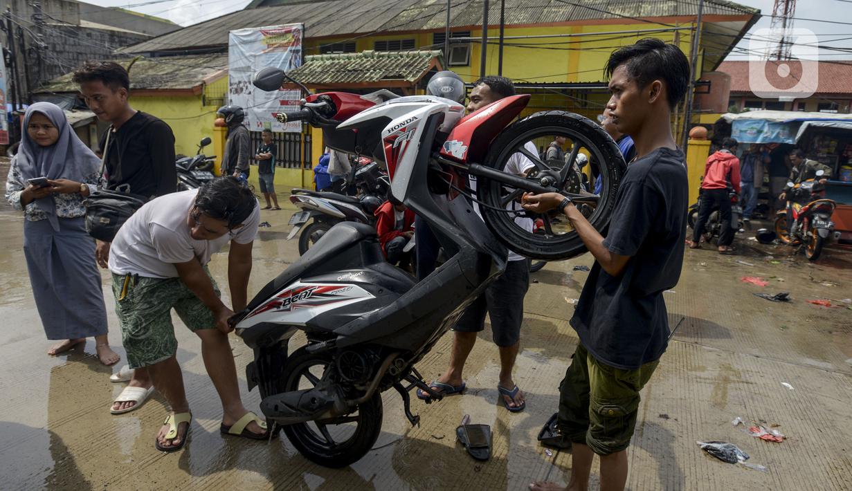 Pengendara motor membuang air yang masuk ke dalam knalpot saat melintasi banjir di Jalan Husein Nastranegara Perapatan Rawa Bokor, Tangerang, Sabtu (1/2/2020). Hujan deras yang mengguyur sejak Jumat (31/1) malam menyebabkan sejumlah kawasan di Tangerang terandam air. (merdeka.com/Imam Buhori)