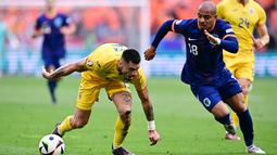 Pemain Belanda, Donyell Malen, berusaha melewati pemain Rumania, Denis Dragus, pada babak 16 besar Euro 2024 di Fussball Arena, Munchen, Selasa (2/7/2024). (AFP/Tobias Schwarz)