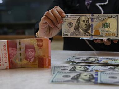 Aktivitas karyawan saat menunjukkan uang rupiah dan dolar AS di salah satu tempat penukaran mata uang asing di Jakarta, Senin (13/1/2025). (Liputan6.com/Angga Yuniar)