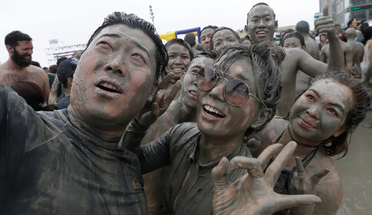 Warga berselfie selama Festival Lumpur Boryeong di Pantai Daecheon di Boryeong, Korea Selatan, (22/7). Festival lumpur tahunan ke-20 ini selalu mengadakan berbagai perlombaan yang menggunakan arena berlumpur. (AP Photo/Ahn Young-joon)