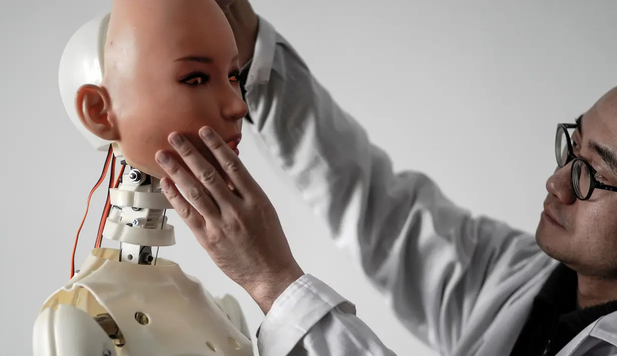 Seorang insinyur menempelkan wajah boneka seks ke kepala robot di sebuah laboratorium pabrik EXDOLL di Dalian, China, Kamis (1/2). EXDOLL menciptakan bonek seks pintar. (AFP PHOTO/FRED DUFOUR)