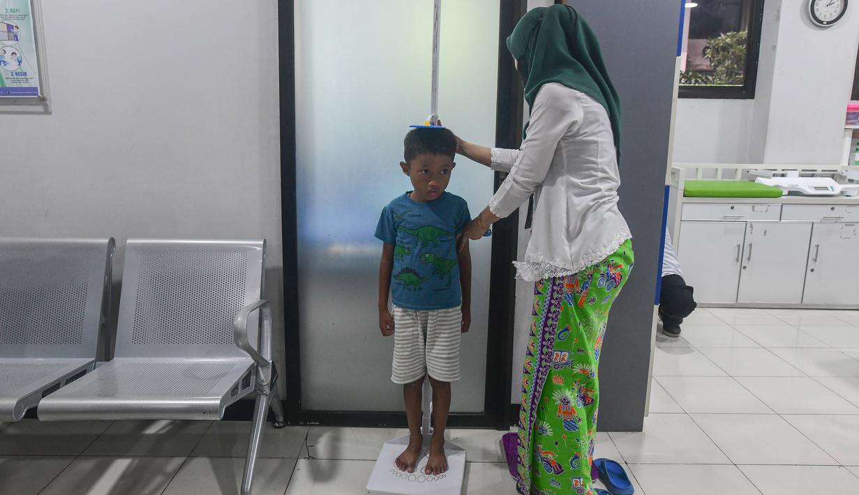 Ia menilai puskesmas tersebut telah memiliki sarana dan prasarana yang sangat memadai, bahkan mendekati standar rumah sakit umum daerah di sejumlah kota. Tampak dalam foto, salah satu tenaga medis sedang melakukan pengukuran tinggi badan anak di Puskesmas Kebayoran Lama, Jakarta, Jumat (9/1/2026). (merdeka.com/Arie Basuki)