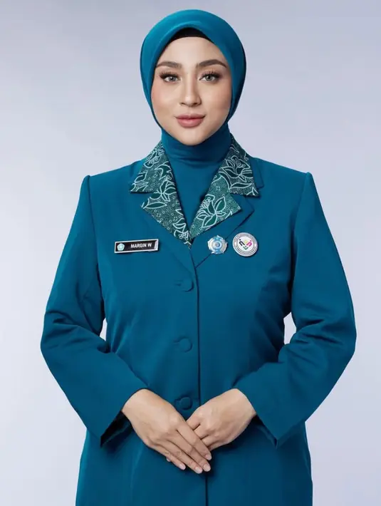 Margin tampil elegan dengan pakaian serba birunya. Terdiri dari inner kemeja batik motif bunga hijau dipadukan blazer sebagai luaran. [@aldiphotoofficial]