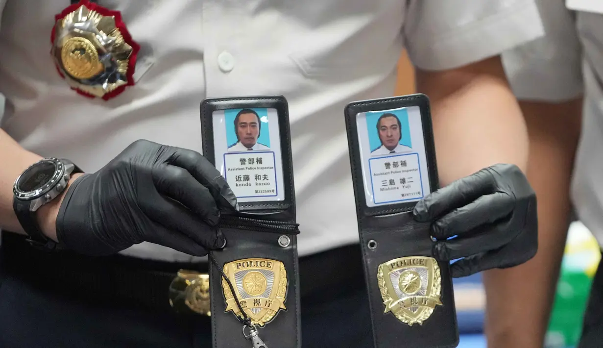 Dari penggeledahan, petugas menyita sejumlah barang bukti yang memperkuat dugaan adanya aktivitas cyber crime, di antaranya atribut yang menyerupai seragam dan tanda pengenal Kepolisian Jepang; puluhan unit telepon genggam dan perangkat komputer; perangkat penguat (booster) serta pengacak sinyal; serta berbagai perangkat elektronik pendukung lainnya. Tampak dalam foto, seorang petugas Imigrasi menunjukkan lencana polisi Jepang palsu yang disita dari warga negara Jepang yang diduga terlibat dalam sindikat penipuan daring (online), di Bogor, Jawa Barat, Rabu 4 Maret 2026. (AP Photo/Achmad Ibrahim)