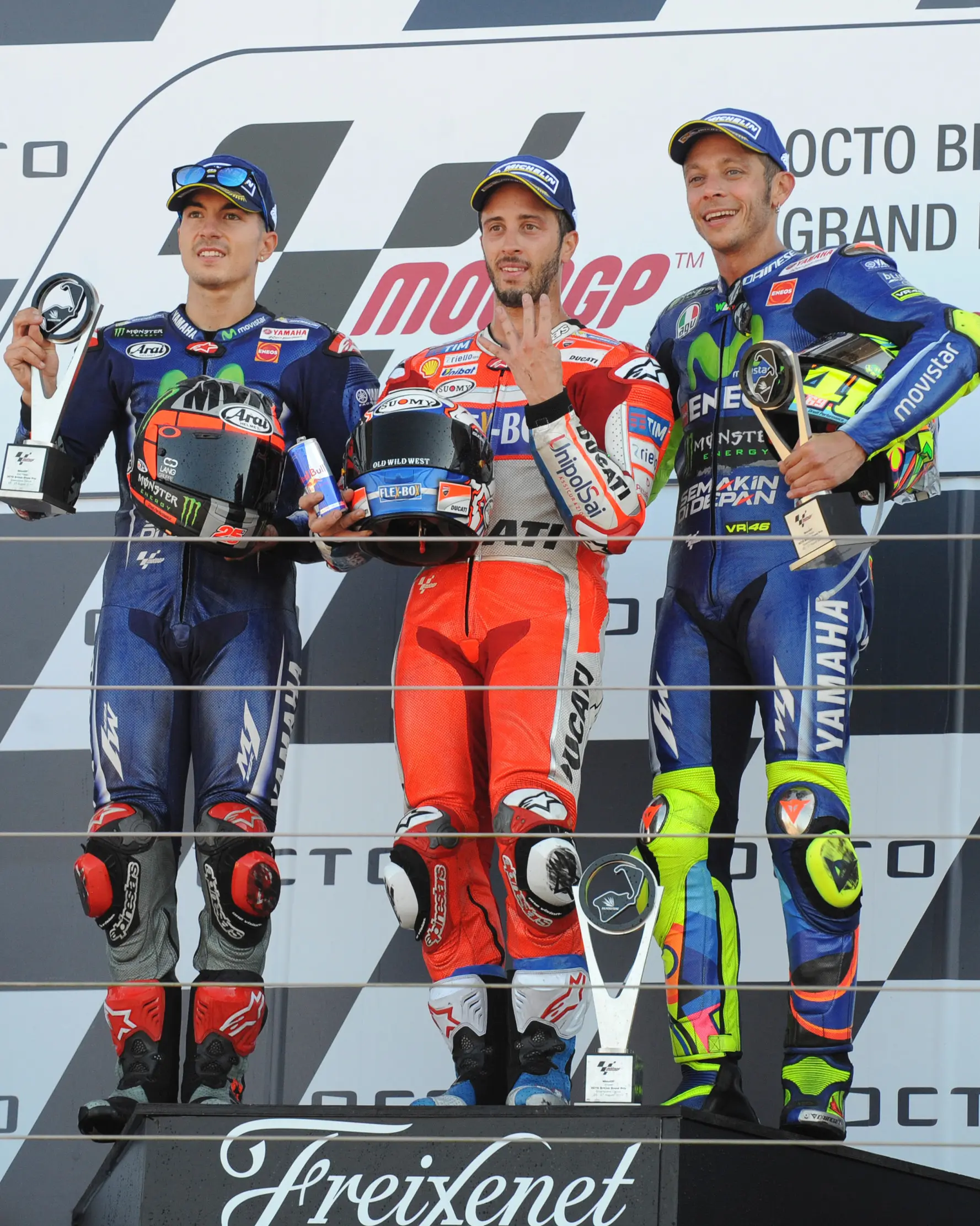 Pembalap Ducati Andrea Dovizioso, berpose dengan dua pembalap Yamaha Maverick Vinales dan Valentino Rossi, setelah berhasil finish di urutan terdepan pada GP Inggris di Sirkuit Silverstone, Minggu (27/8). (AP Photo/Rui Vieira)