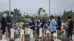 Keluarga berdoa untuk kerabat mereka di lokasi pemakaman korban virus corona COVID-19 di TPU Keputih, Surabaya, Jawa Timur, Sabtu (17/7/2021). Di Kota Surabaya terdapat dua tempat lahan pemakaman khusus blok COVID-19 yakni TPU Keputih dan TPU Babat Jerawat. (JUNI KRISWANTO/AFP)