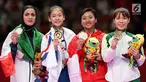 Karateka putri Indonesia, Cokorda Istri Agung Sanistyarani (kedua kanan) menunjukkan medali perunggu usai memenangkan pertandingan di babak final nomor Kumite 55 kg di Arena Karate JCC Senayan, Jakarta, Minggu (26/8). (Liputan6.com/Fery Pradolo)