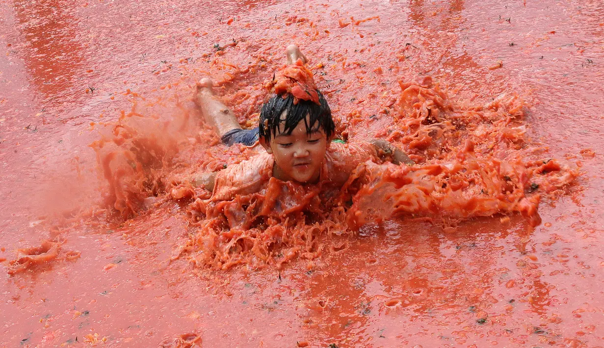 Seorang anak melompat ke dalam kolam berisi tomat selama Festival Tomat di Hwacheon, Korea Selatan, 5 Agustus 2017. Festival untuk merayakan panen tomat ini berlangsung dari 4 - 7 Agustus. (AP Photo/Ahn Young-joon)