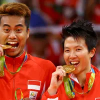Pasangan ganda campuran Indonesia, Tontowi Ahmad dan Liliyana Natsir mengigit medali emas usai mengalahkan lawannya asal Malaysia Peng Soon Chan dan Liu Ying Goh pada final bulutangkis di Riocentro Pavilion 4 , Brasil. (REUTERS/Mike Blake)