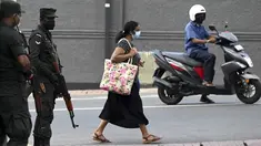 Seorang pejalan kaki melewati tentara yang berjaga di sepanjang jalan di Kolombo pada Sabtu (2/4/2022). Pasukan yang dipersenjatai dengan senapan serbu otomatis dikerahkan di Sri Lanka untuk mengendalikan massa, beberapa jam setelah presiden menyatakan keadaan darurat. (KODIKARA / AFP)