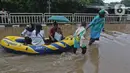 Warga menaiki perahu karet saat melintasi kawasan DI Panjaitan, Jakarta, Selasa (25/2/2020). Hujan yang mengguyur Jakarta sejak dini hari tadi membuat kawasan tersebut terendam banjir sehingga tak bisa dilintasi kendaraan bermotor. (Liputan6.com/Herman Zakharia)