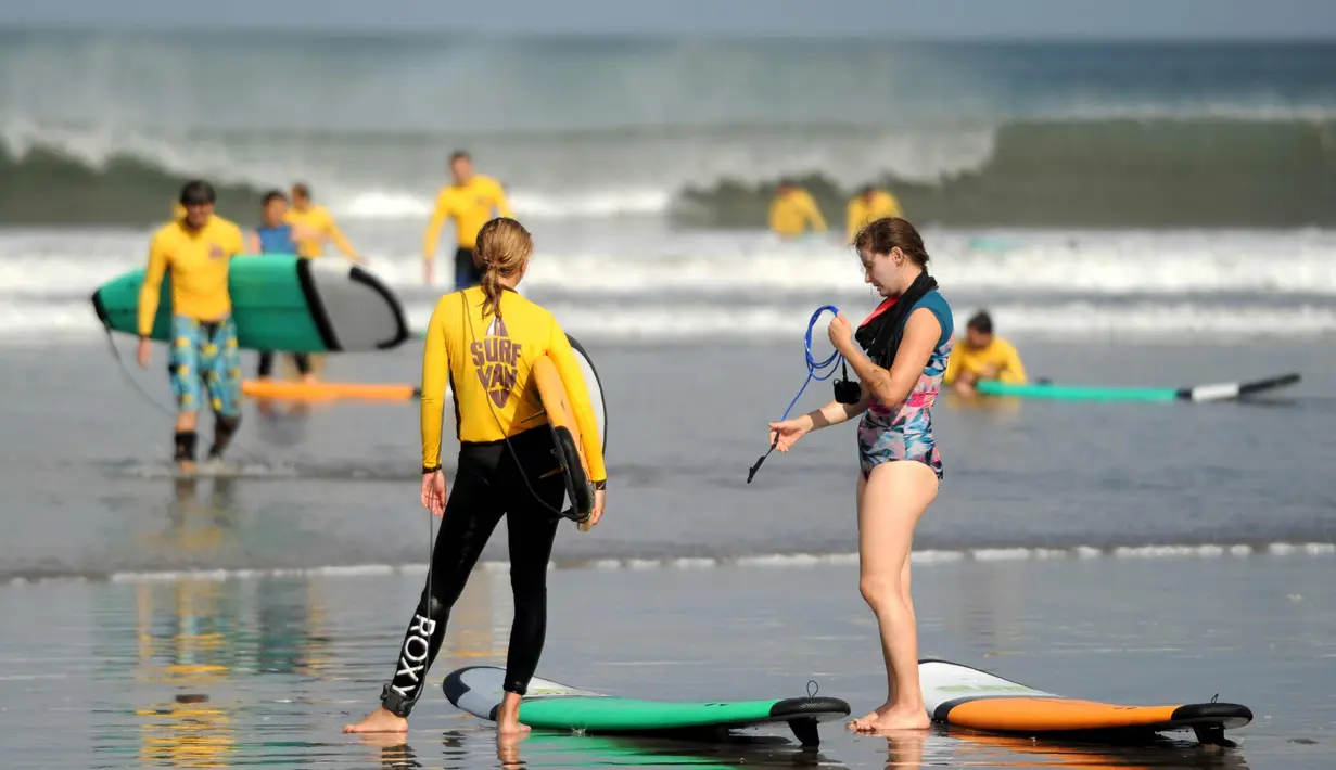 Dua turis bermain surfing di Pantai Kuta di Denpasar, Bali (27/9). Gunung Agung adalah gunung berapi yang besar dengan puncak 3.142 meter di atas permukaan laut. Gunung ini mendominasi pemandangan timur Bali. (AFP Photo/Sony Tumbelaka)