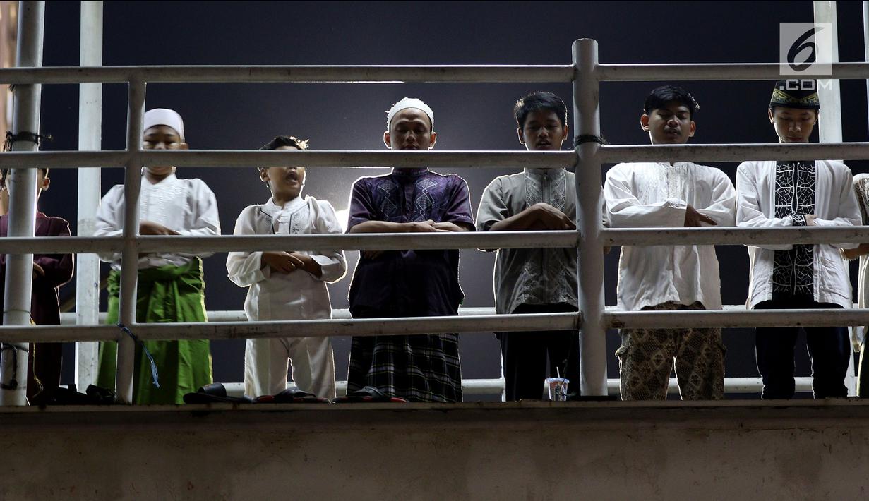 Sejumlah warga melaksanakan salat tarawih di atas JPO Musala Miftahul Jannah di Kawasan Pasar Gembrong, Jakarta, Kamis (17/5). Membludaknya jemaah yang hadir mengakibatkan mereka meluber hingga ke badan jalan dan JPO. (Liputan6.com/JohanTallo)
