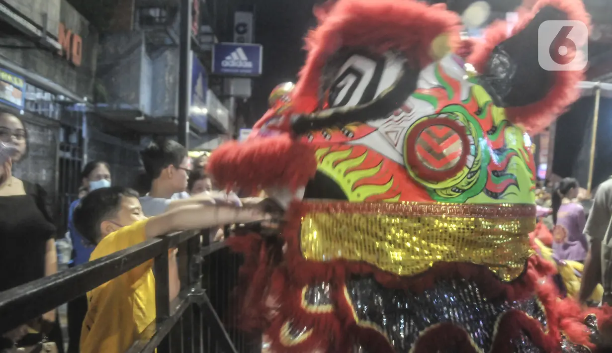 Seorang anak memberikan angpao kepada Barongsai saat perayaan Cap Go Meh di Jalan Surya Kencana, Bogor, Jawa Barat, Minggu (5/2/2023). Dalam perayaan Cap Go Meh di Jalan Surya Kencana ini ribuan orang hadir memeriahkan malam pawai Liong dan Barongsai. (merdeka.com/Iqbal S Nugroho)
