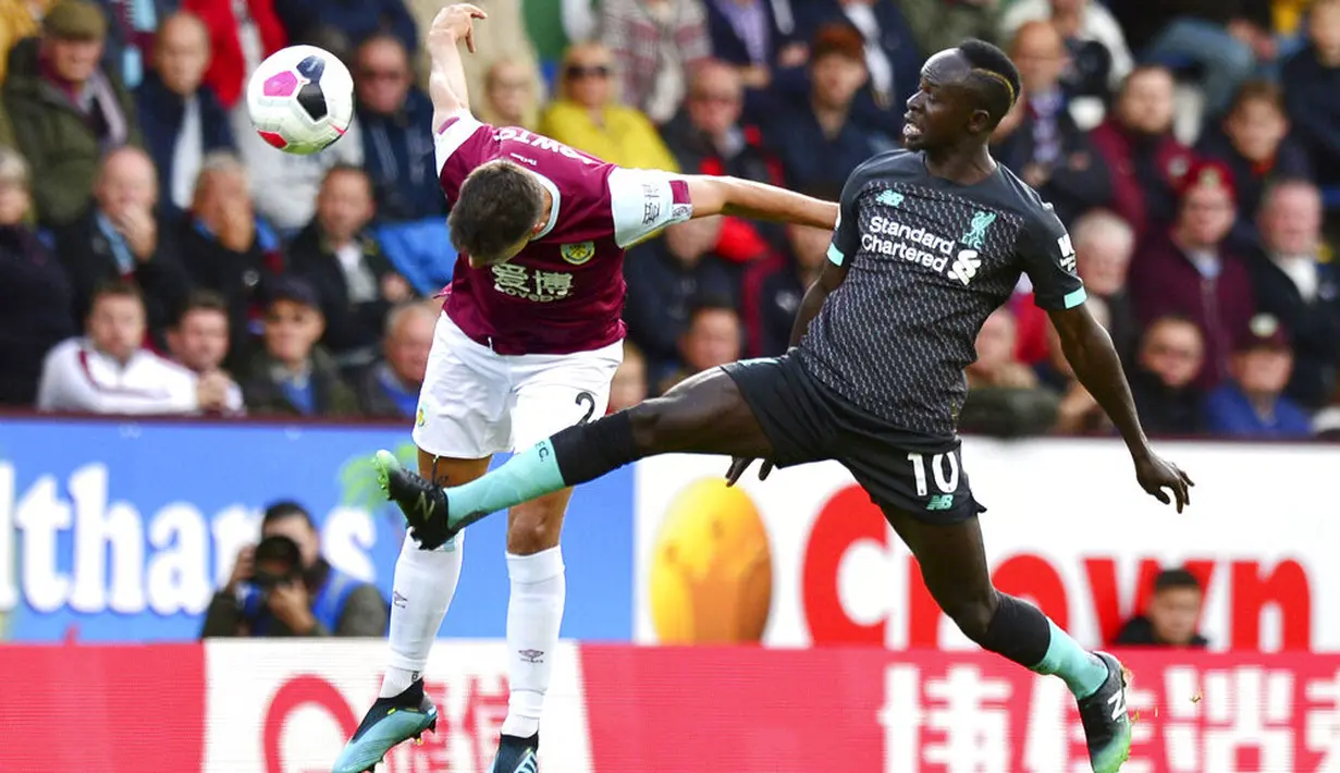 Penyerang Liverpool, Sadio Mane, berebut bola dengan pemain Burnley, Matthew Lowton, pada laga Premier League 2019 di Stadion Turf Moor, Sabtu (31/8). Liverpool menang 3-0 atas Burnley. (AP/Anthony Devlin)