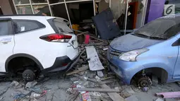 Sebuah mobil Toyota Rush dan Avanza menjadi incaran jarahan korban gempa dan tsunami di Palu Grand Mal, Palu, Jumat (5/10). Warga korban gempa bumi mengambil ban dan interior mobil. (Liputan6.com/Fery Pradolo)