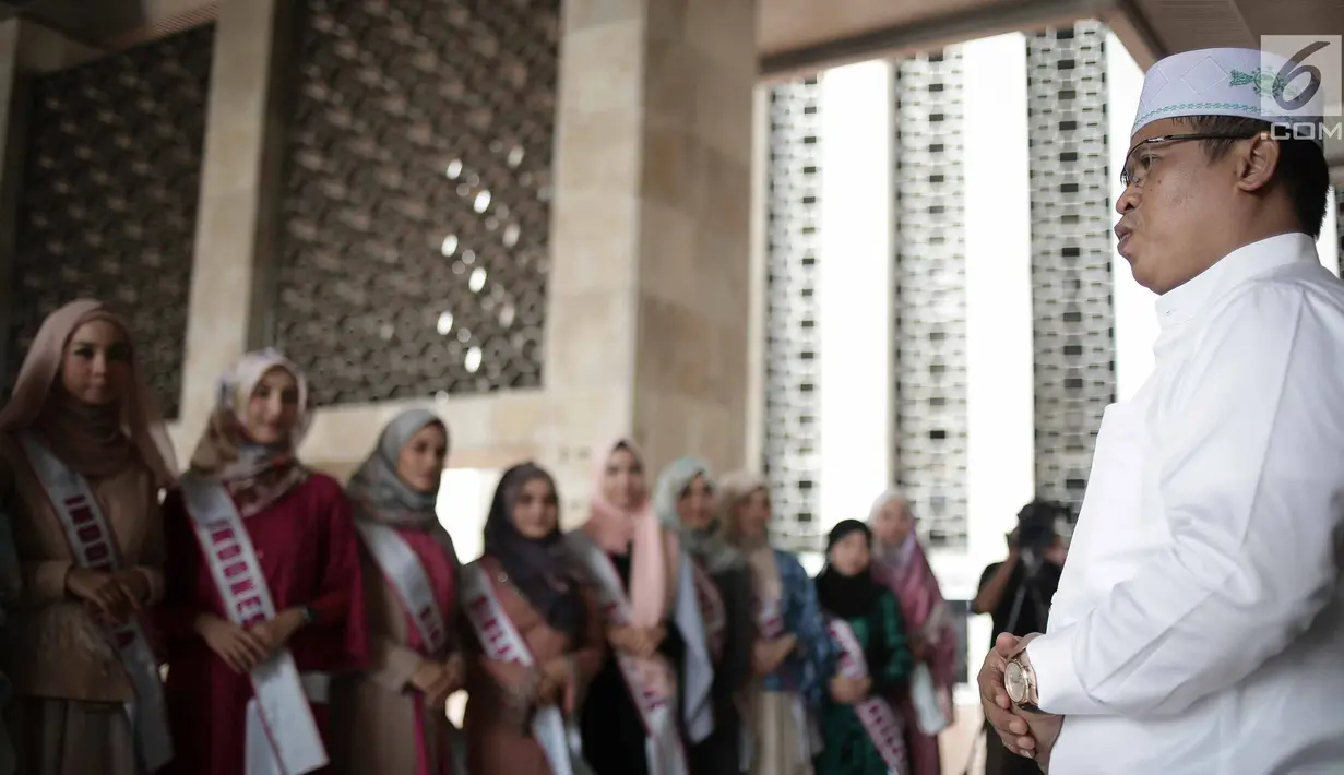 Kepala Protokol Masjid Istiqlal, Abu Hurairah bersama peserta Puteri Muslimah Asia 2018 saat tour Mesjid Istiqlal, Jakarta, Kamis (3/4). Masing masing negara mengutus tiga kontestan. Peserta berumur 15 sampai 25 tahun. (Liputan6.com/Faizal Fanani)