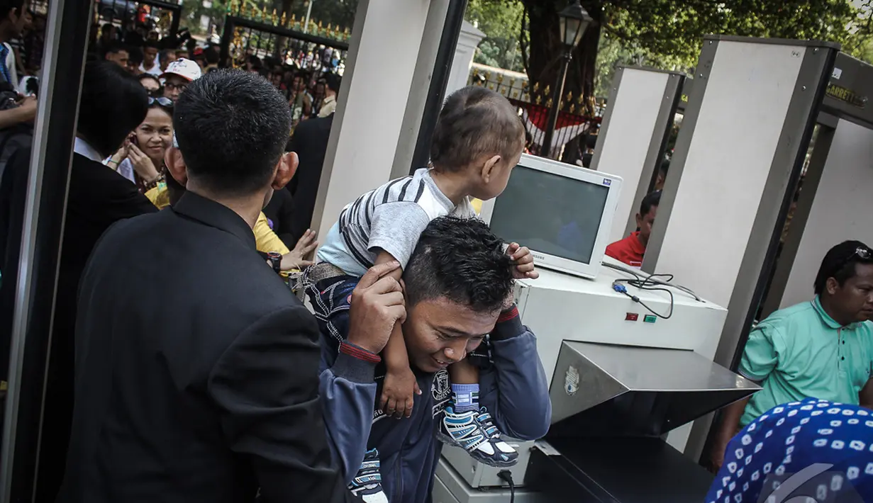 Seorang lelaki dengan seorang bocah dipundaknya berhasil masuk ke Istana negara usai menjalani pemeriksaan, Jakarta, Senin (20/10/2014) (Liputan6.com/Faizal Fanani)
