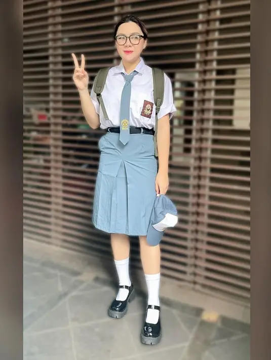 <p>Vicky Shu tampil bak siswi cupu dengan seragam rapi yang dimasukan lengkap dengan dasi dan sabuk hitamnya. Ia juga membawa backpack, topi, kacamata besar, dan kaos kaki panjang putih dengan sepatu hitamnya. (Instagram/vickyshu)</p>