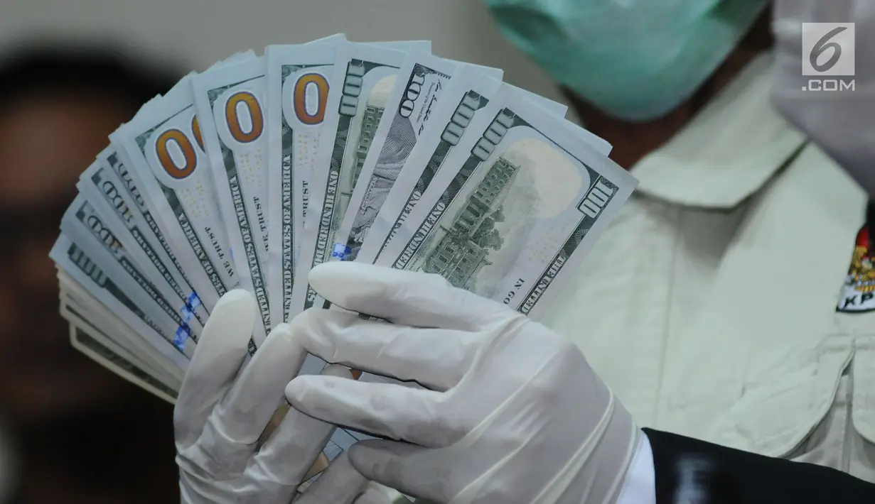 Petugas KPK menunjukkan barang bukti uang pecahan dollar hasil operasi tangkap tangan Bupati Jombang, Nyono Suharli Wihandoko di Gedung KPK, Jakarta, Minggu (4/2). KPK menyita uang Rp 25,5 Juta dan 9.500 US Dollar. (Liputan6.com/Helmi Fithriansyah)