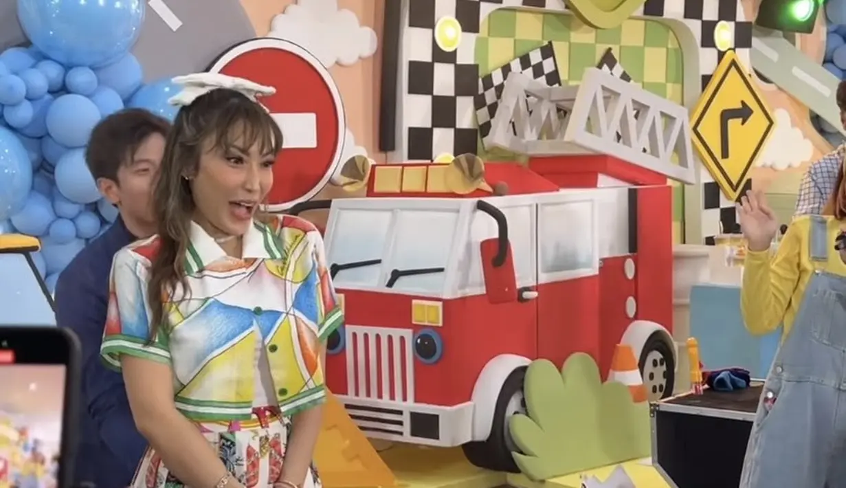 Ayu Dewi juga hadir dengan atasan kemeja lengan pendek crop top motif colorful. Dipadukan rok pleated motif. [@tya_ariestya]